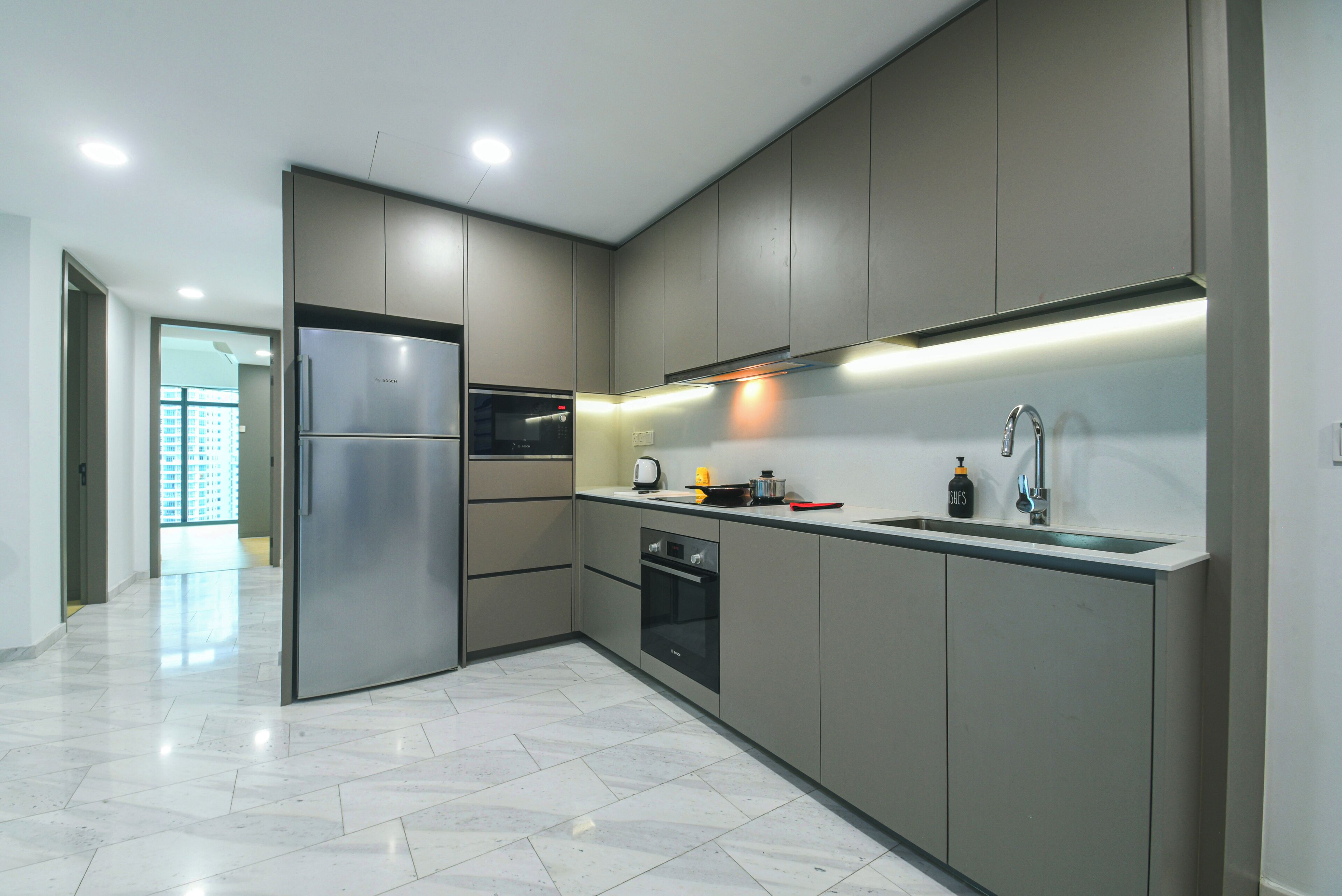 A modern kitchen with stainless steel appliances, a built-in oven, and a large island with a sink and countertop.