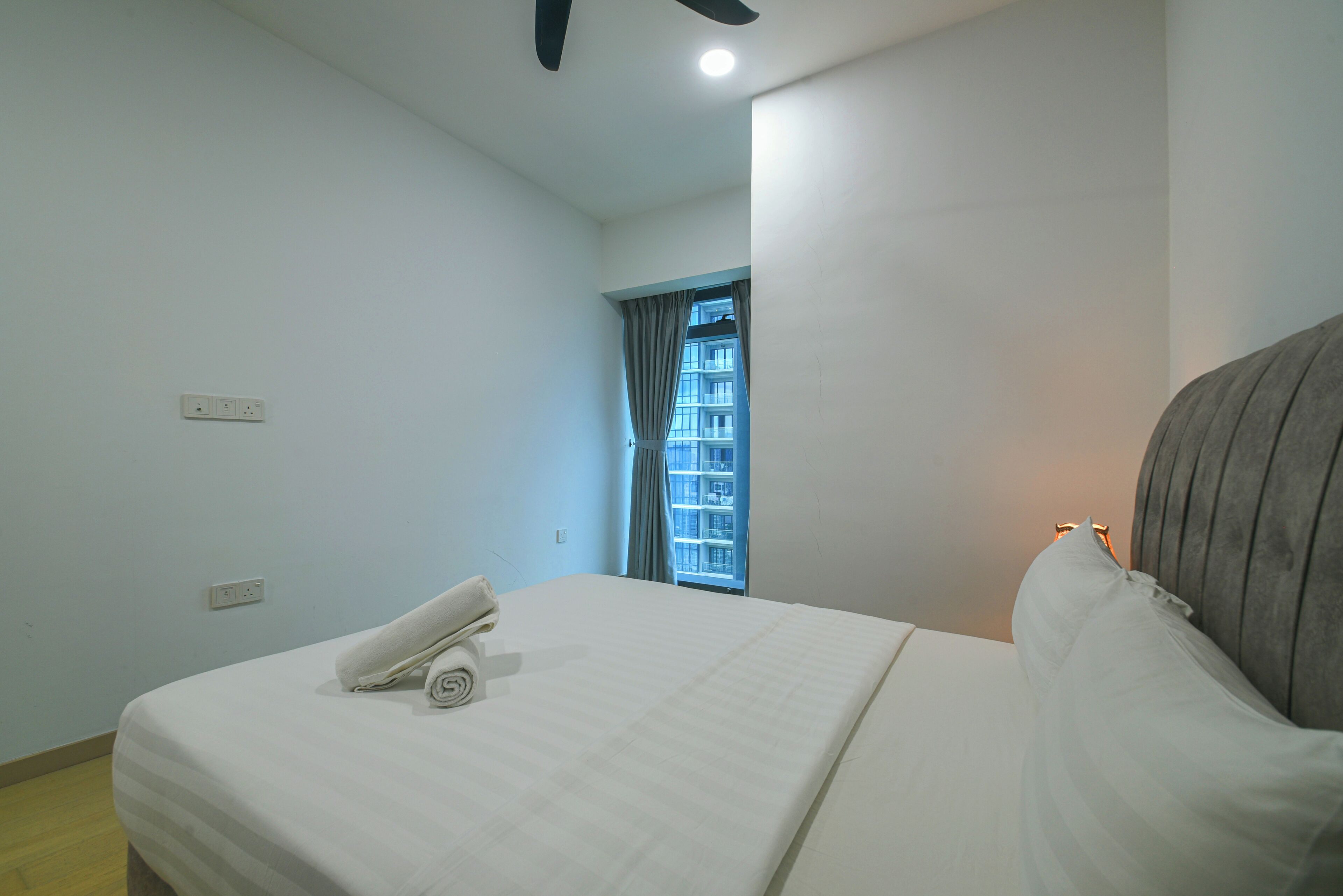 Une chambre d’hôtel avec un lit, une fenêtre avec des rideaux et une vue sur un bâtiment à l’extérieur.