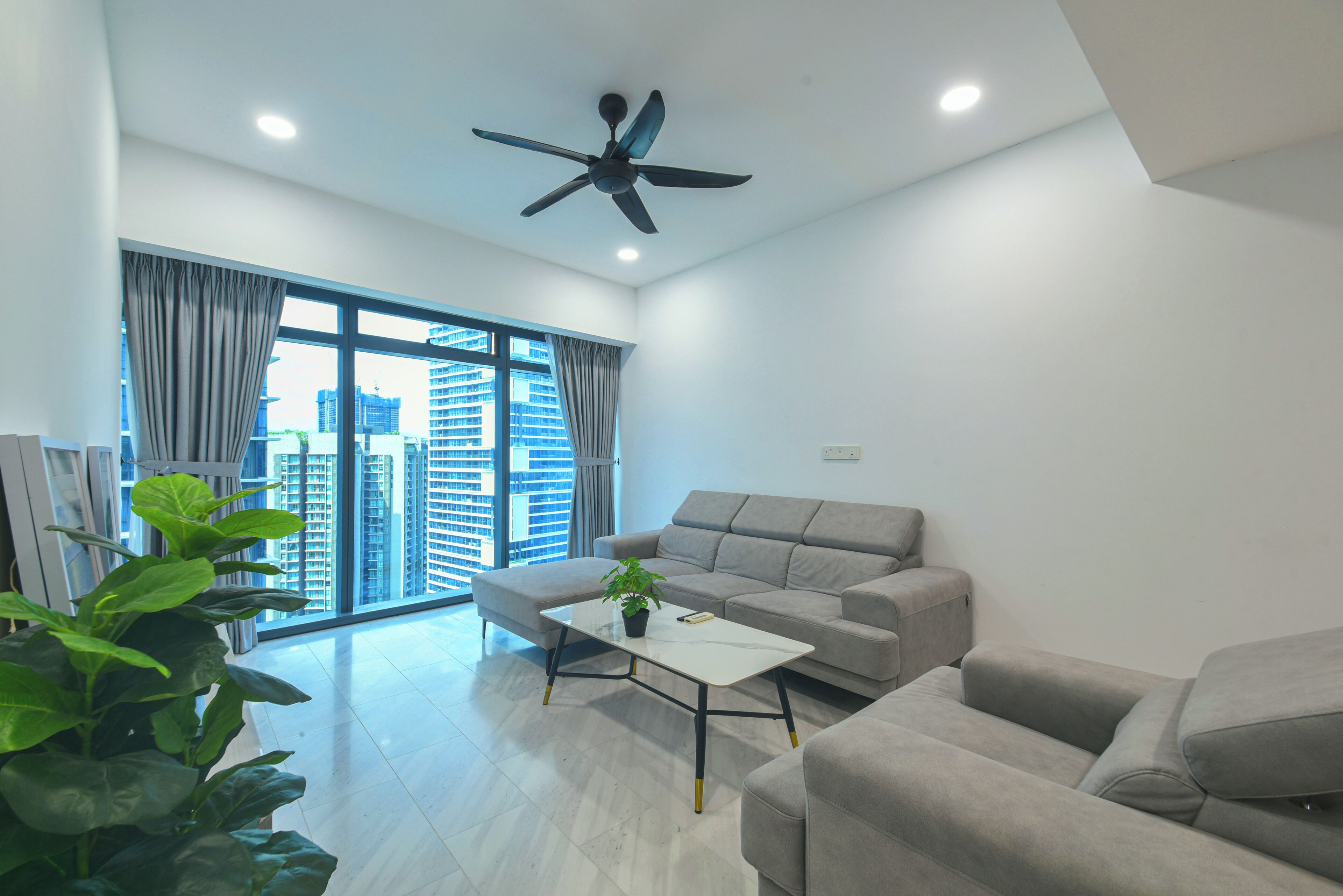 A modern living room with a sofa, a coffee table, and a ceiling fan.