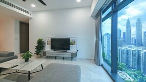Una sala de estar moderna con una televisión de pantalla plana, un sofá, una mesa de centro y una planta en maceta.