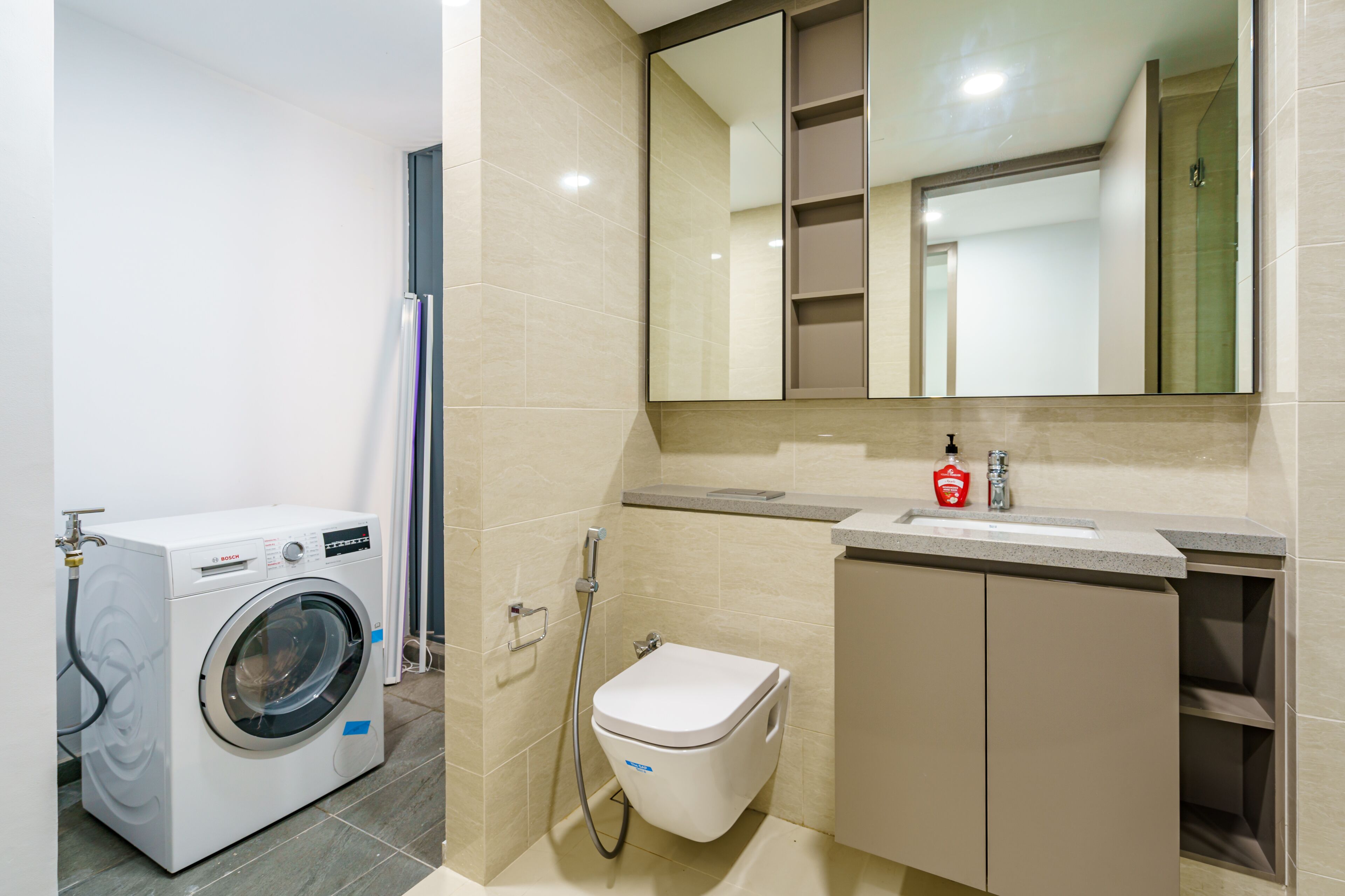 A compact bathroom with a washing machine, toilet, and sink.