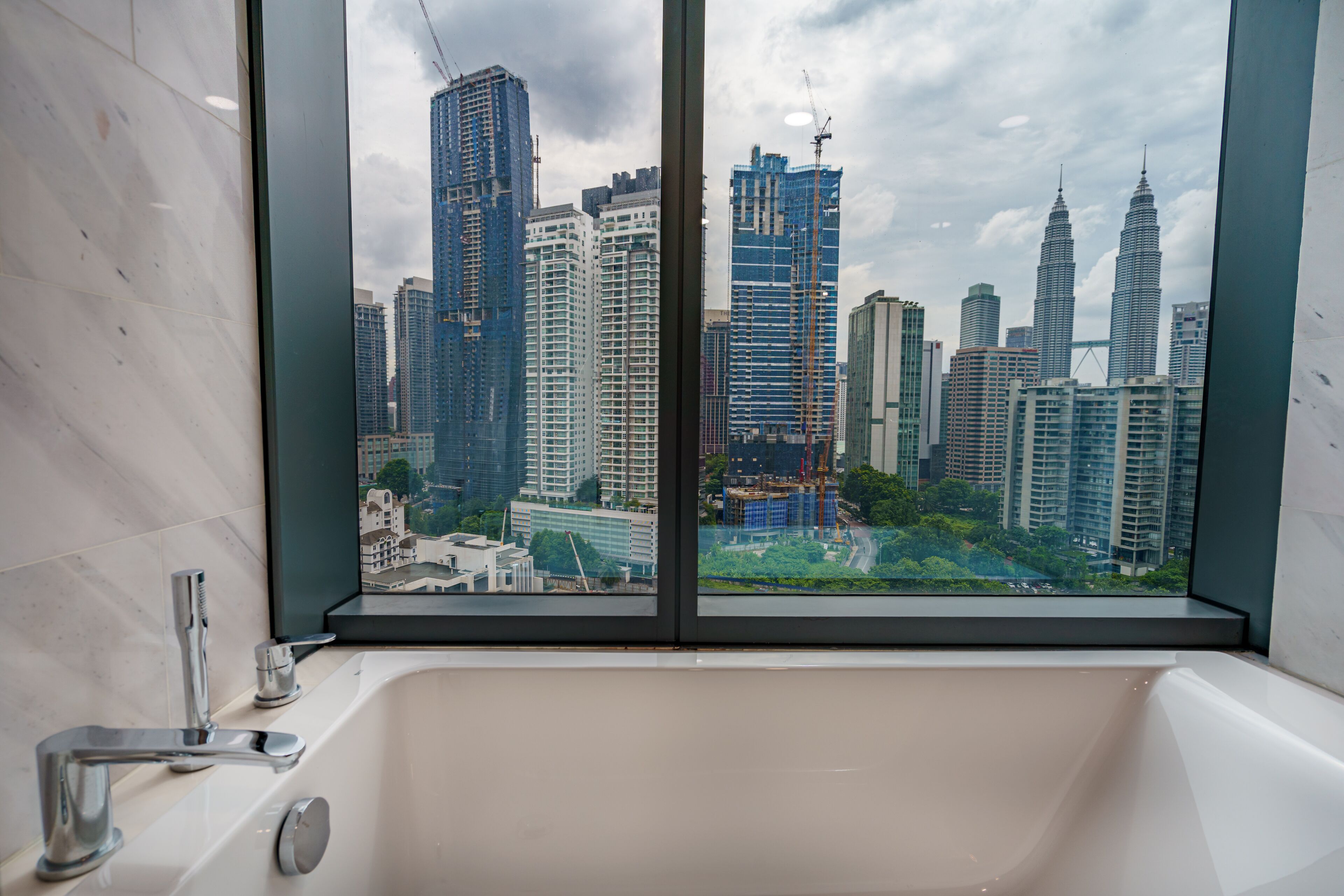 Une salle de bain avec une baignoire et une vue sur le paysage urbain, visible par une fenêtre.