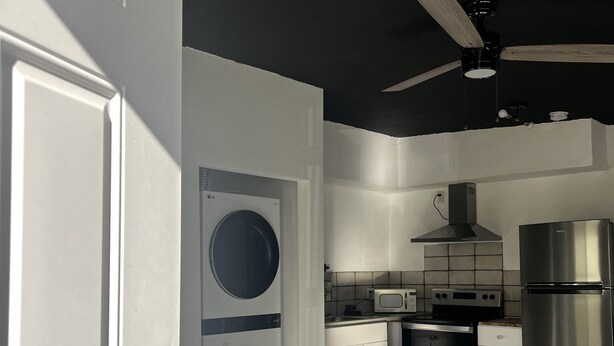 A modern kitchen with a built-in washer and dryer, stainless steel appliances, and a ceiling fan. - Remodeled quiet and spacious home. (Blythe)