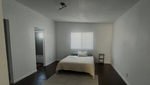 A bedroom with a bed, a window, and a door leading to another room. - Remodeled quiet and spacious home. (Blythe)