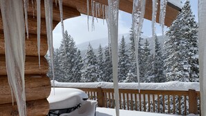 A wooden cabin with a snow-covered deck and icicles hanging from the ceiling.