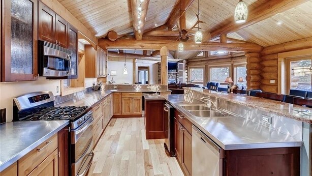A spacious kitchen with wooden cabinetry, stainless steel appliances, and a large island.