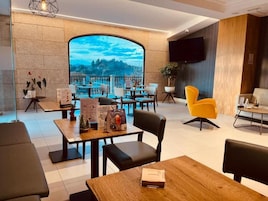 Un restaurante moderno con un amplio ventanal que ofrece vistas panorámicas. Mesas y sillas dispuestas para comer.