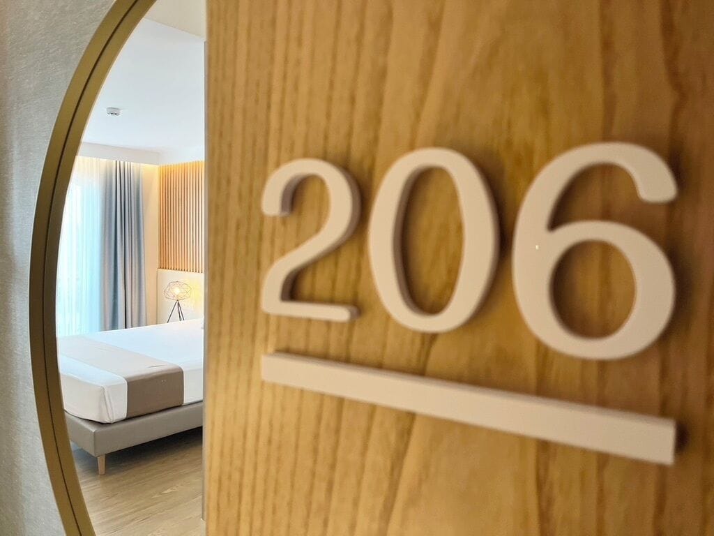 Een houten bord met het nummer 206, wat een hotelkamer aangeeft.
