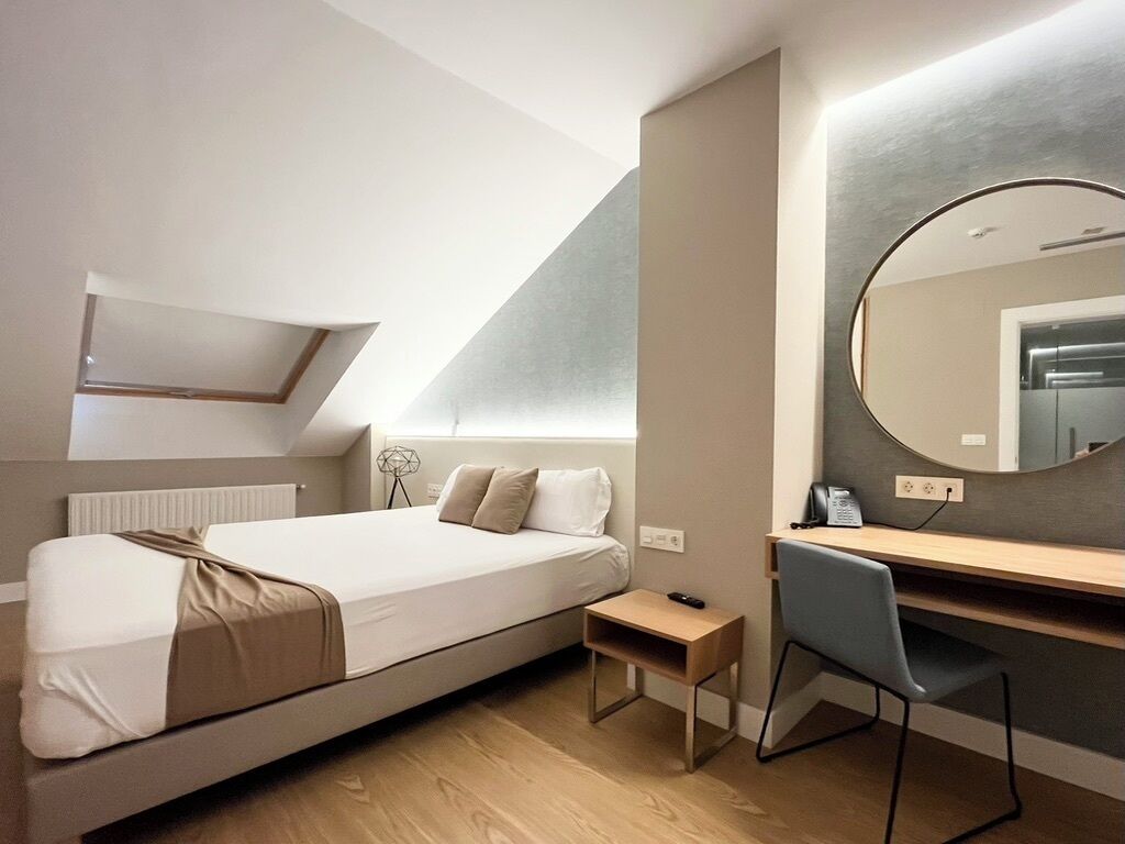 Un dormitorio moderno con cama tipo loft, un escritorio y un espejo grande.