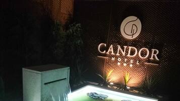 A water feature with plants and a sign for the Candor Hotel.