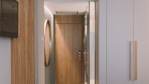 A modern hallway with a wooden door, a glass partition, and a flat-screen TV mounted on the wall. - Hotel Candor (A Lama)