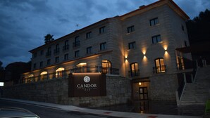 A hotel with a stone facade, multiple balconies, and a sign reading "CANDOR HOTEL". - Hotel Candor (A Lama)