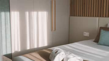 A neatly made bed with a white and beige bedspread, a pair of white towels, and a single pillow.