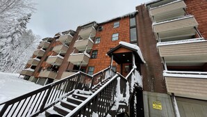 A multi-story residential building with balconies, a staircase, and a warning sign about ice and snow. - Ski condo close to multiple resorts (Mendon)