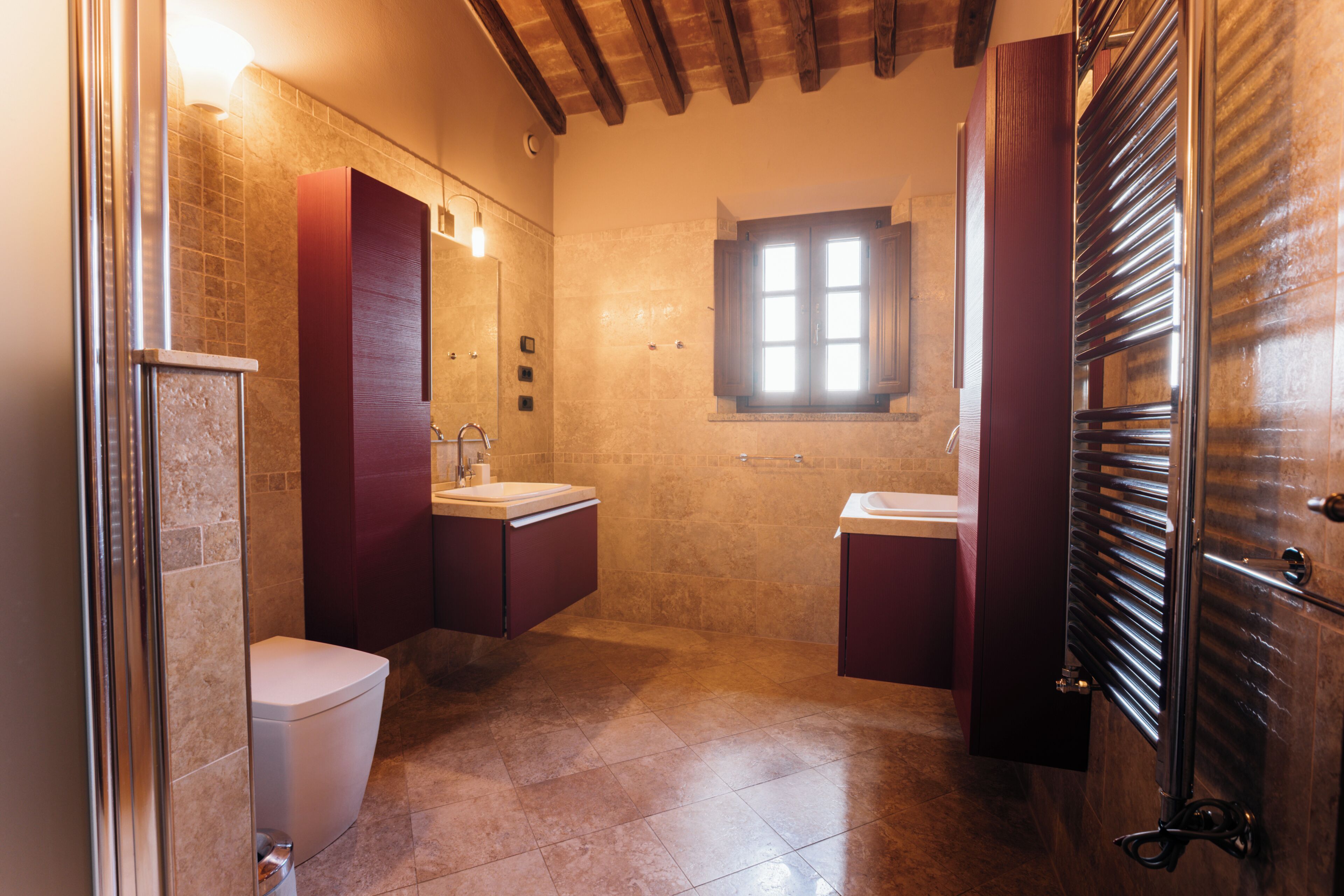 Une salle de bain avec des toilettes, deux lavabos, un miroir et une fenêtre.