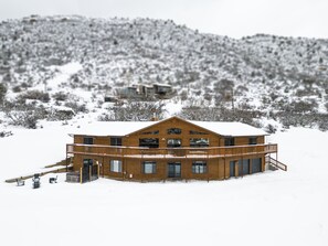 Une cabane en bois dotée d’un balcon, entourée d’un paysage enneigé.