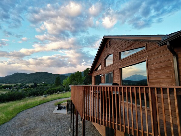 Une cabane en bois dotée d’une terrasse offrant une vue sur un paysage montagneux.