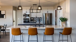A modern kitchen with a central island, stainless steel appliances, and pendant lighting. - Gorgeous Retreat with Mountain Views, Open Living, Game Room, Hot Tub (Glenwood Springs)