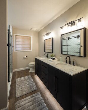 Une salle de bain moderne avec un meuble-lavabo à deux vasques, des toilettes et une fenêtre équipée de stores.