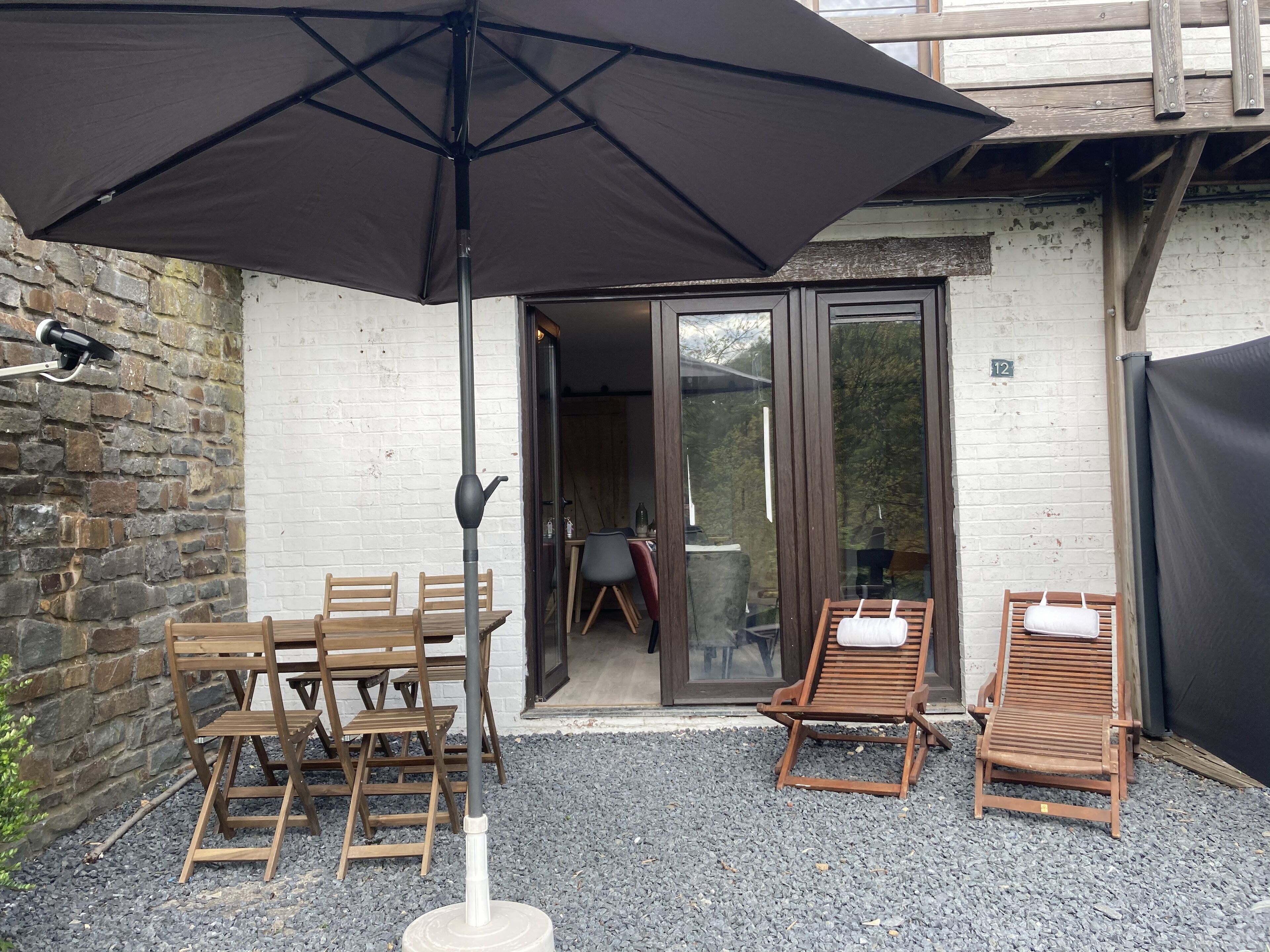 An outdoor seating area with a table and chairs, a wooden bench, and a large umbrella.