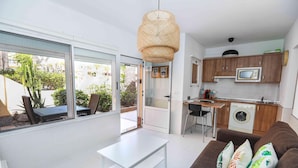 Een modern appartement met een eetgedeelte, een keuken en een woonkamer met een bank en kussens.