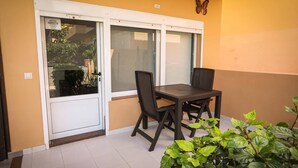 Een balkon met een tafel en stoelen, een schuifdeur en een vlinderdecoratie aan de muur.