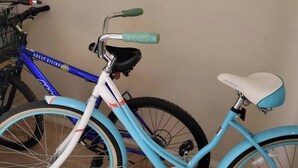 A blue bicycle with a white seat and green grips, leaning against a wall. - Oceanfront Paradise: Your Dream Beachfront Escape (Panama City Beach)