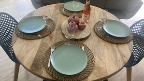 Una mesa de madera redonda con cuatro platos azules, dos copas de vino y una botella.