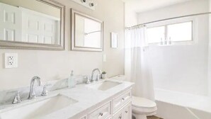 A bathroom with two sinks, a toilet, and a bathtub.