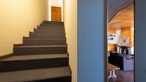 A staircase with carpeted steps leading to a wooden door. - Italianway - Capitano Grandi 5 (Bormio)