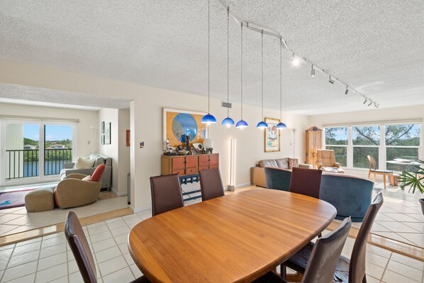 A spacious dining area with a wooden table and chairs, a large window with a view, and a ceiling with track lighting.