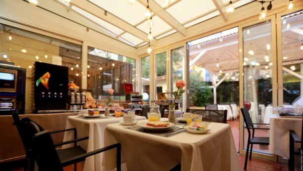 Ein Restaurant mit gedeckten Tischen für das Frühstück, mit einer Auswahl an Speisen und Getränken.