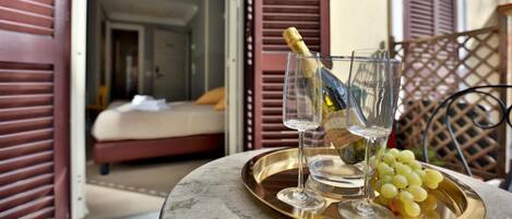 A tray with a bottle of champagne, two glasses, and a bunch of grapes on a table.