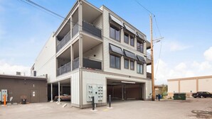 A multi-story building with a garage entrance, a balcony on the second floor, and a utility area with electrical panels.