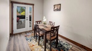 A dining area with a wooden table and chairs, a vase with flowers, and a patterned rug.
