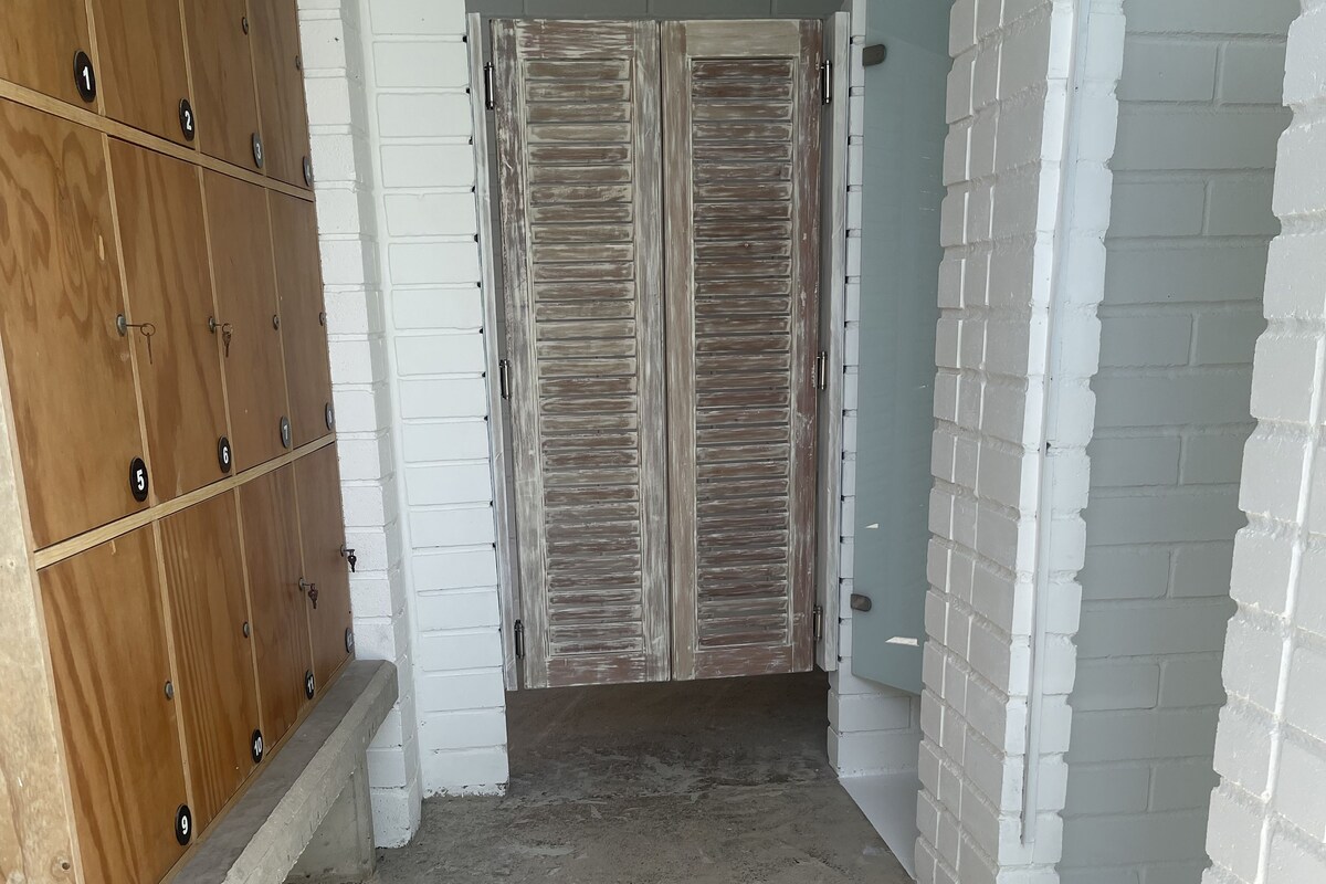 A hallway with a wooden locker area on the left and a door with a rustic finish on the right.