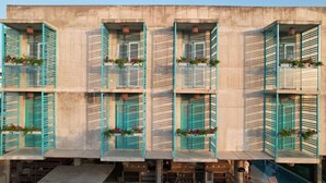 Un edificio de varios pisos con balcones, cada uno con barandilla de metal y plantas en macetas.