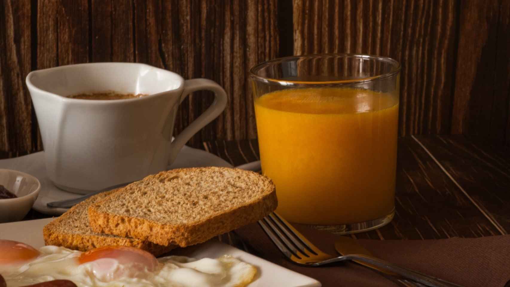 A breakfast setting with toast, eggs, a cup of coffee, and a glass of orange juice on a wooden table.