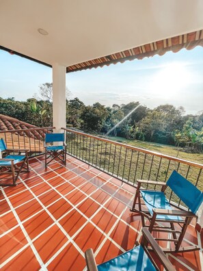 A covered terrace with tiled flooring, a railing, and several blue and wooden chairs. - Hotel la Casona Montañesa (Montenegro)