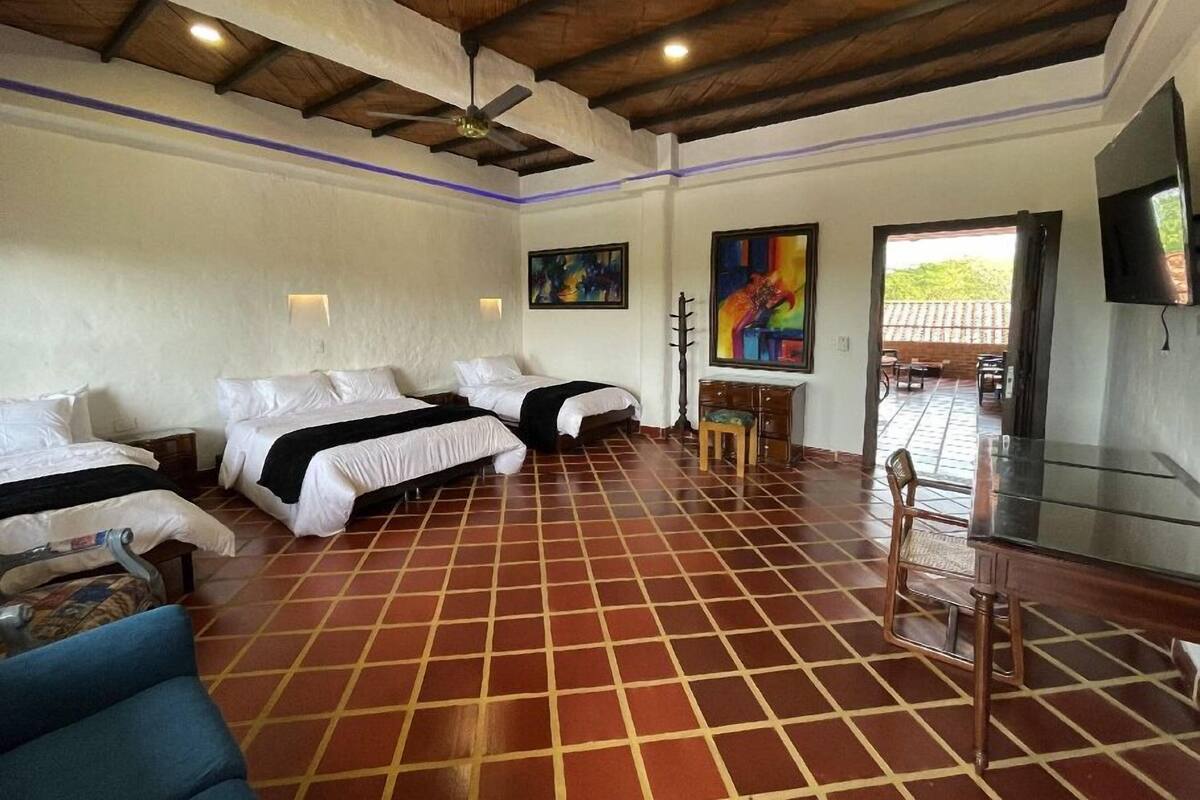 Une chambre d’hôtel avec deux lits, un ventilateur de plafond, une télévision et une vue sur la terrasse extérieure.