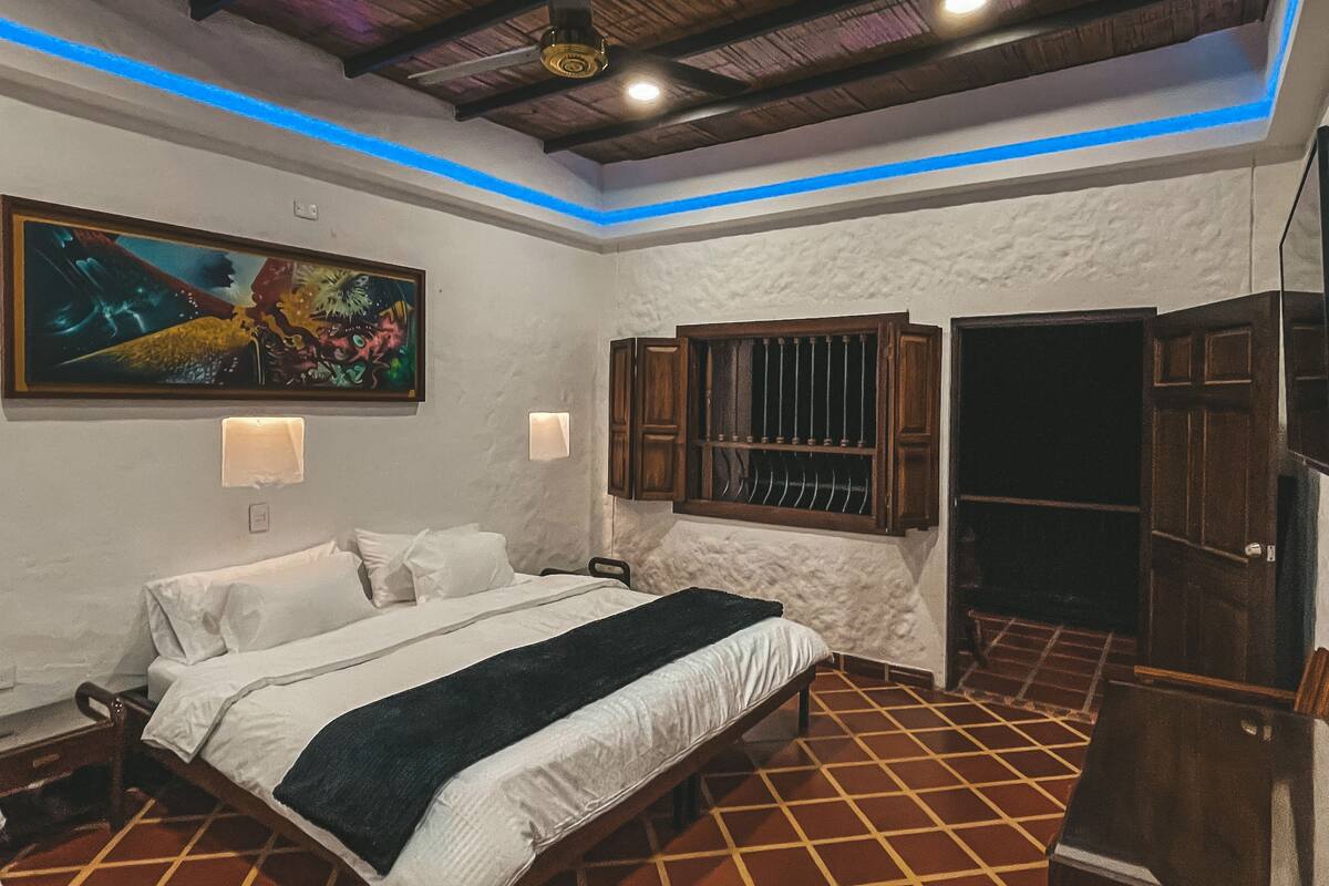 Une chambre à coucher avec un lit, un tableau, une fenêtre avec des volets et une armoire.