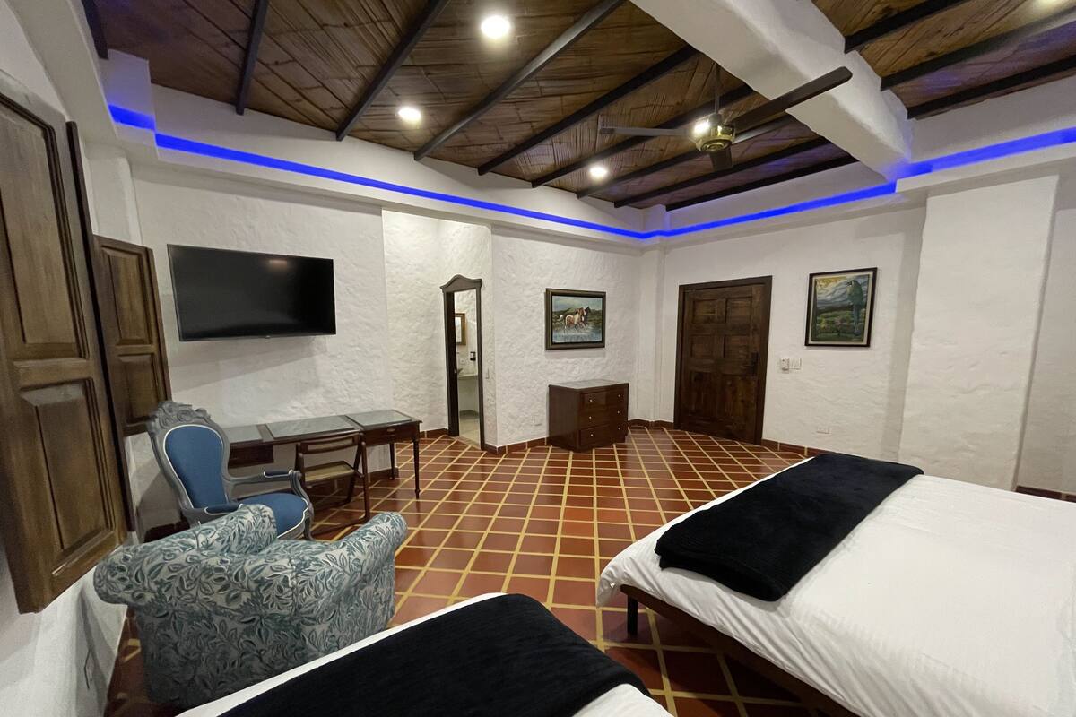 Une chambre avec deux lits, un bureau, une chaise, une télévision et une porte.