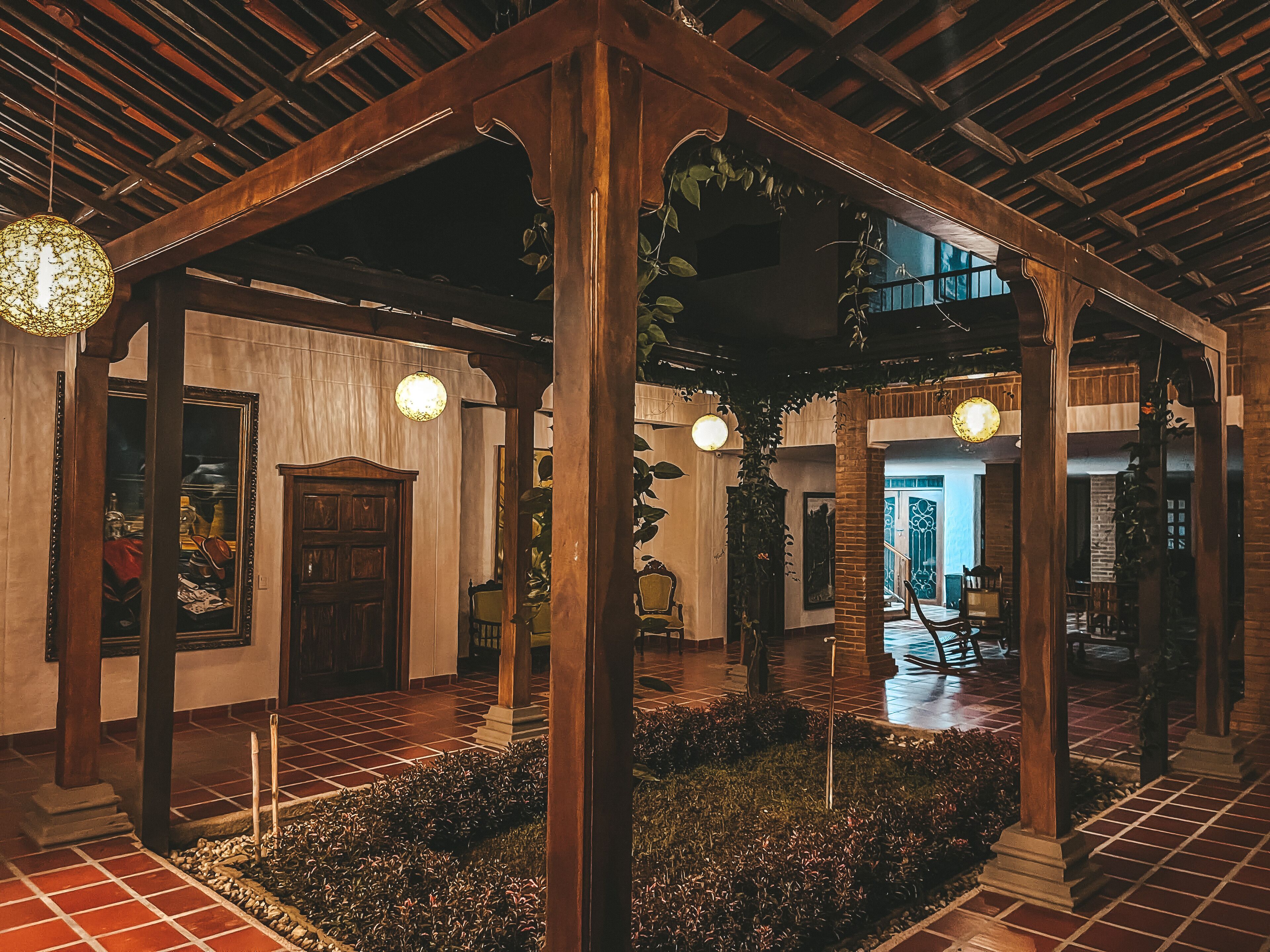 A traditional wooden pavilion with tiled flooring and a central garden area.