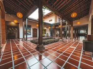 Un patio amplio con suelo de baldosas, pilares de madera y faroles colgantes.