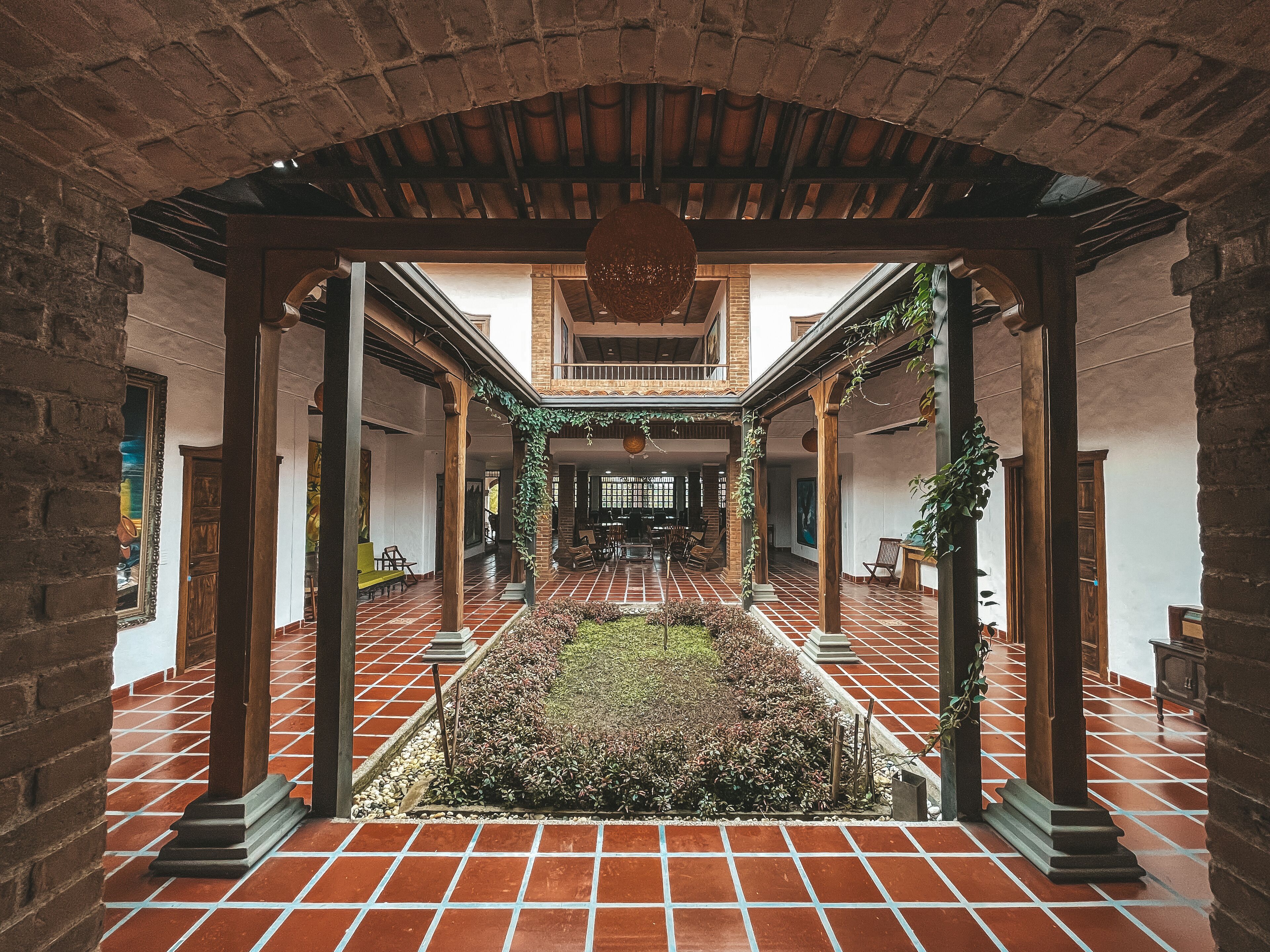 Un patio con suelo de baldosas, paredes de ladrillo y columnas de madera.
