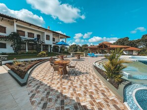 A pool area with a tiled deck, lounge chairs, and a building with a tiled roof. - Hotel la Casona Montañesa (Montenegro)