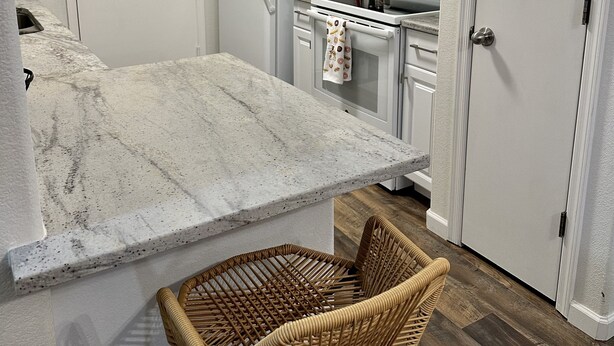 A kitchen with white cabinetry, a microwave, a refrigerator, and a stove. There is a small island with a chair. - Close to everything!  2bed/2 bath (Surprise)