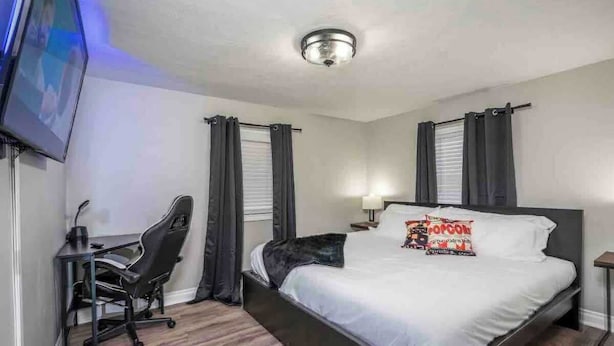 Une chambre d’hôtel avec un lit, un bureau et une chaise, une télévision et un luminaire au plafond.
