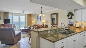 A spacious living area with a dining table, chairs, a sofa, and a kitchen island with a sink. - Gulf Front Condo in PCB, FL.
2 bedroom 2 bath with one set of bunks (Panama City Beach)