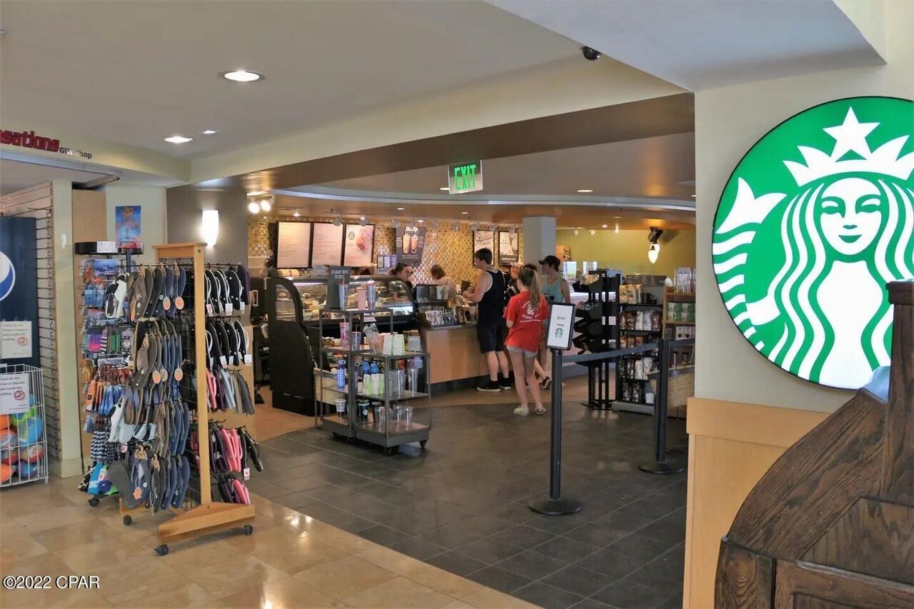 Una Starbucks dentro de un centro comercial, con una exhibición de bolsas y un mostrador con gente.